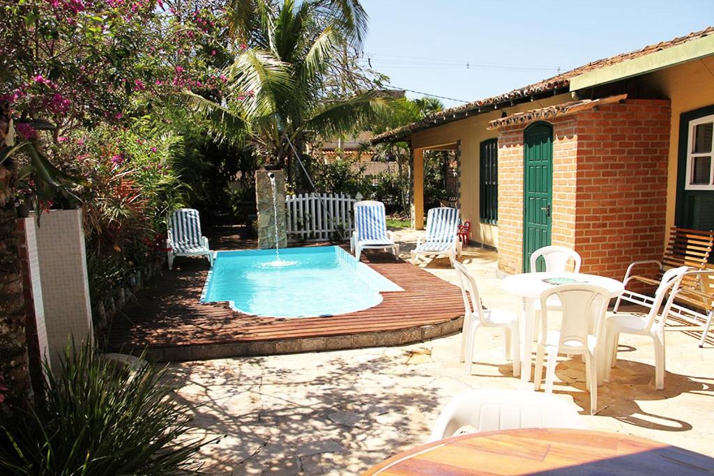 a patio with chairs and a small swimming pool at Casa com Piscina Exuberante in Cabo Frio