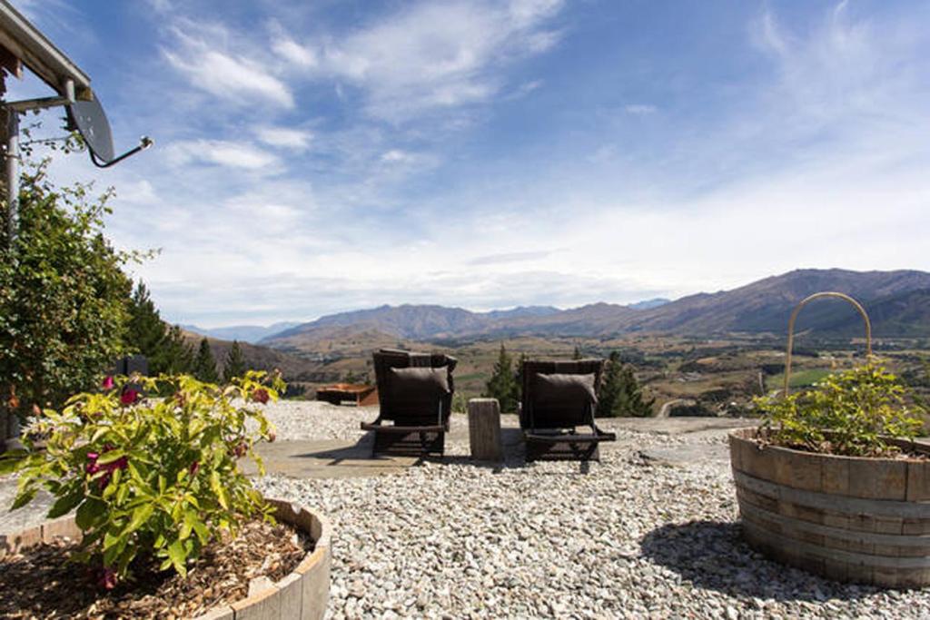 two chairs on a patio with mountains in the background at Creagh Cottage and Homestead in Arrowtown