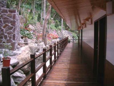 a wooden walkway leading to a building with a garden at Jing Leh Resort Hotel in Baihe