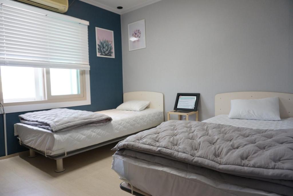 釜山的住宿－AIRPORT Guesthouse，一间卧室设有两张床和窗户。