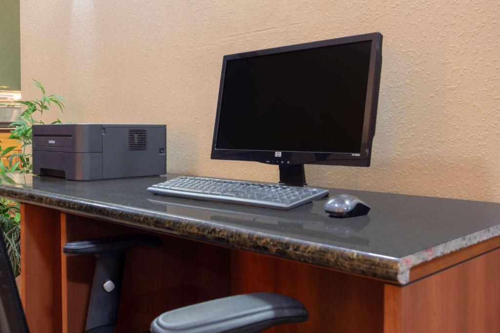ein Computermonitor, eine Tastatur und eine Maus auf dem Schreibtisch in der Unterkunft AmericInn by Wyndham West Bend in West Bend