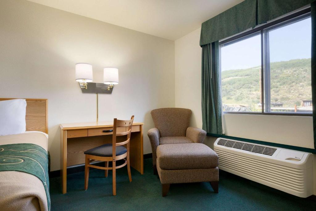 a hotel room with a bed and a desk and a chair at Travelodge by Wyndham Yampa in Yampa