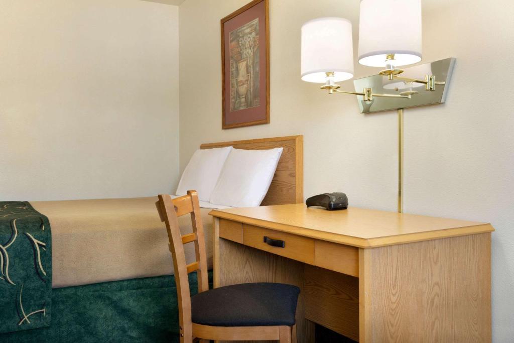 a room with a bed and a desk with a telephone at Travelodge by Wyndham Yampa in Yampa