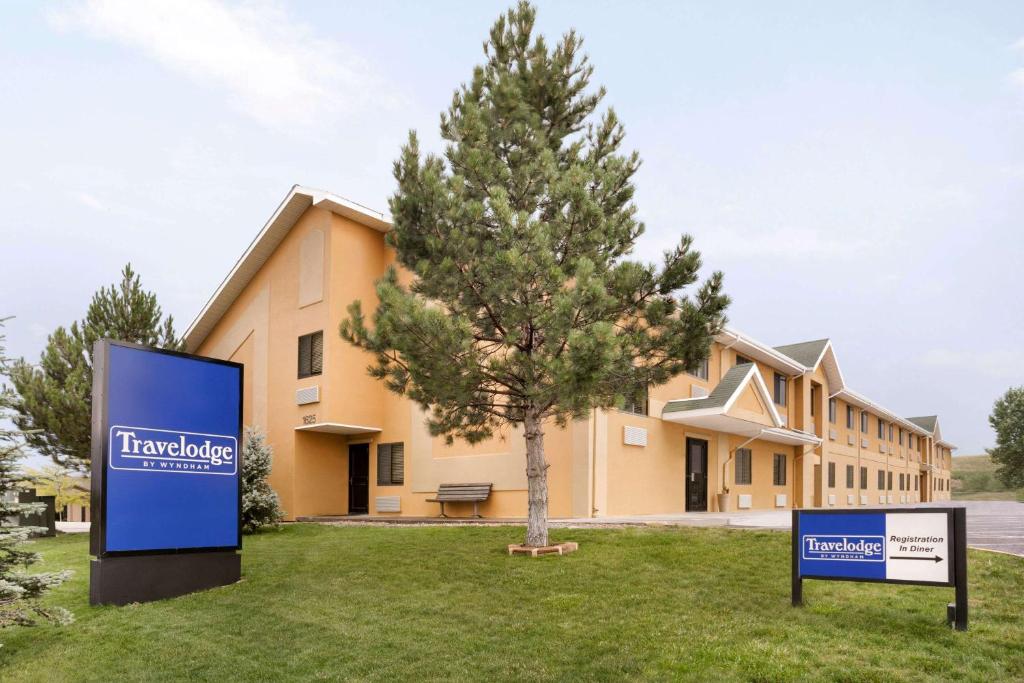 a building with a sign in front of a tree at Travelodge by Wyndham Cheyenne in Cheyenne