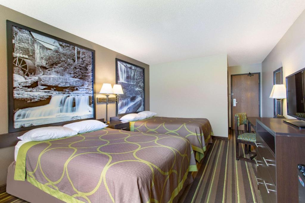 a hotel room with two beds and a flat screen tv at Super 8 by Wyndham Weston WV in Weston
