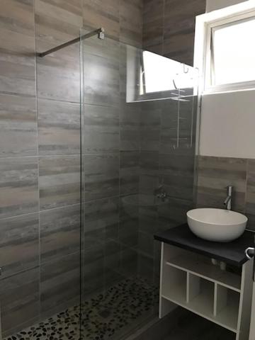 y baño con ducha acristalada y lavamanos. en Modern rooms available close to the beach in Humewood en Port Elizabeth