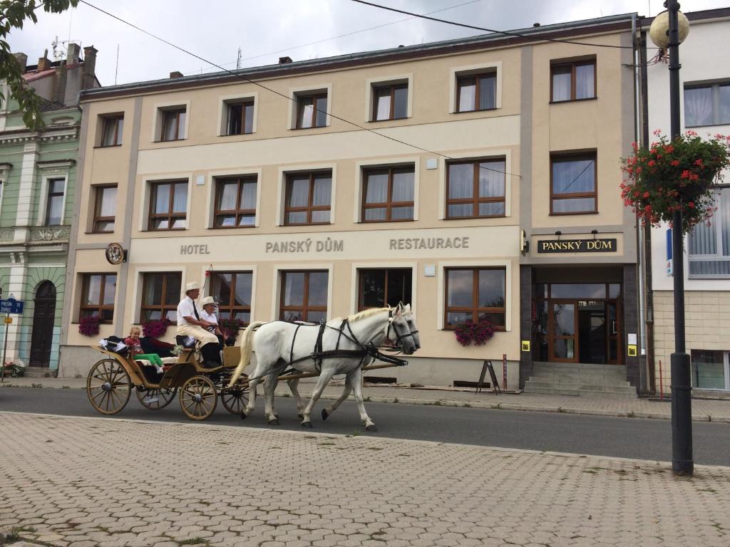 uma carruagem puxada por cavalos numa rua em frente a um edifício em Hotel Panský dům em Blovice