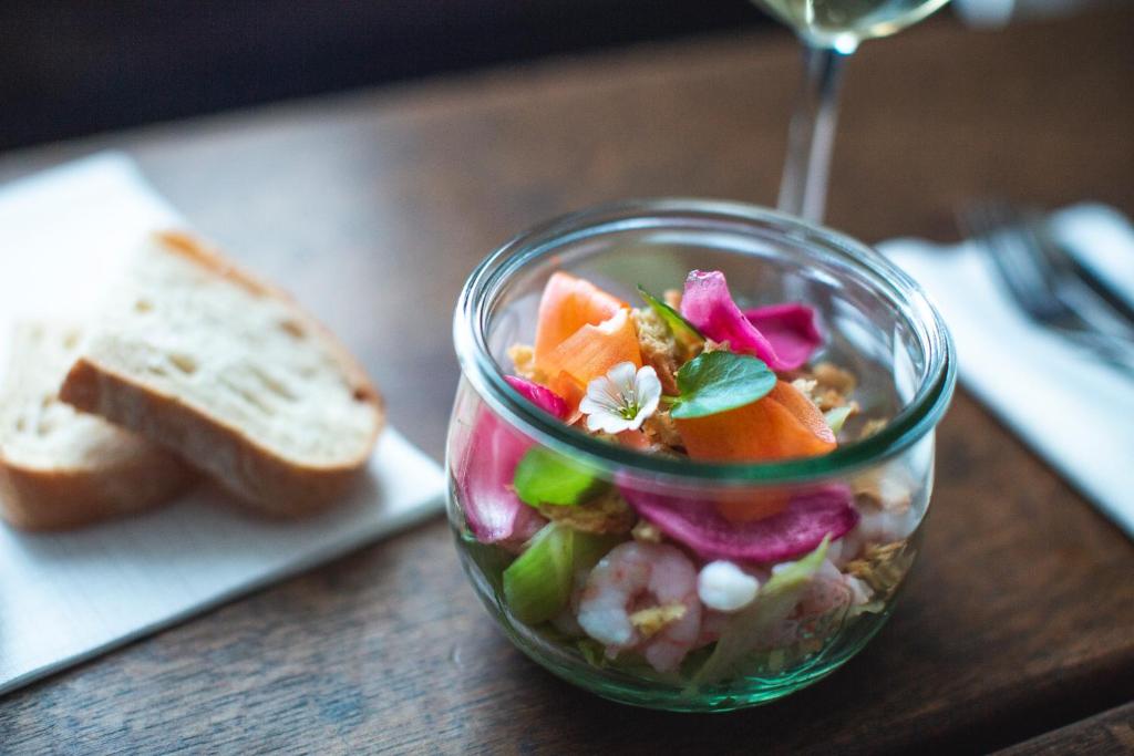 a salad in a glass bowl on a table with a sandwich at Hotel Icefiord in Ilulissat