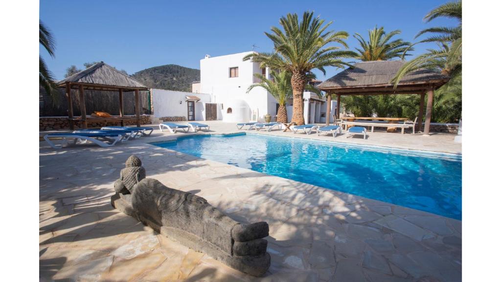 una piscina con una casa y palmeras en Villa Daniel is in a great location just 5 mins by taxi into Playa Den Bossa, en Ibiza