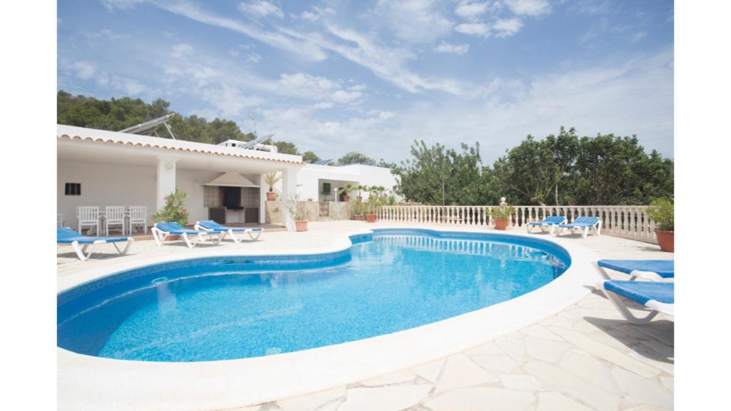 a swimming pool with blue chairs and a house at Can Tunicu has amazing sea views and is located in a quiet area near to San Antonio in San Antonio