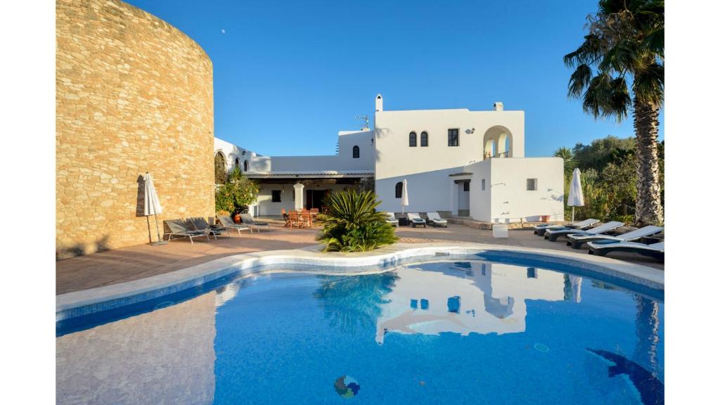 a swimming pool in front of a white house at Can Mestre is a huge Villa with stunning sunset views near to San Antonio in San Antonio Bay