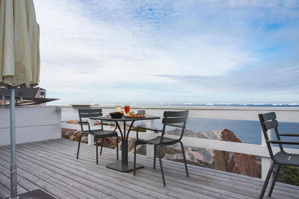 a table and chairs on a deck overlooking the water at Hotel Icefiord in Ilulissat