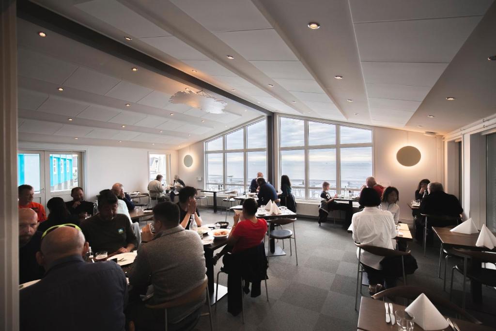 a group of people sitting at tables in a restaurant at Hotel Icefiord in Ilulissat