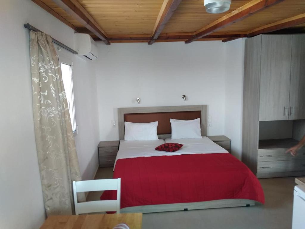 a bedroom with a large bed with a red blanket at Hotel Aglaia in Kalamaki