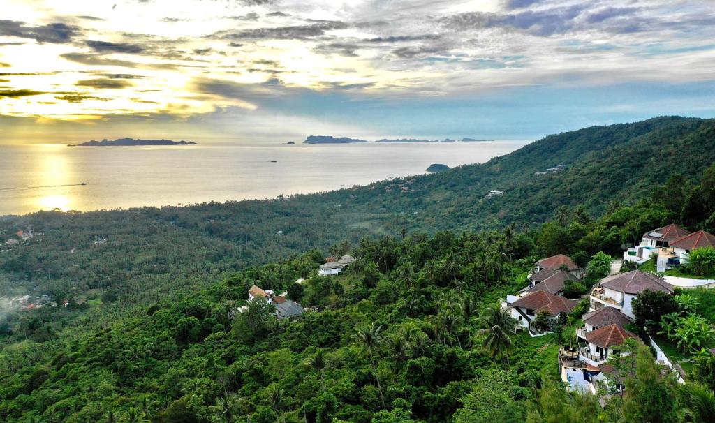 a view of a hill with houses and the water at Samui Paradise Village in Nathon