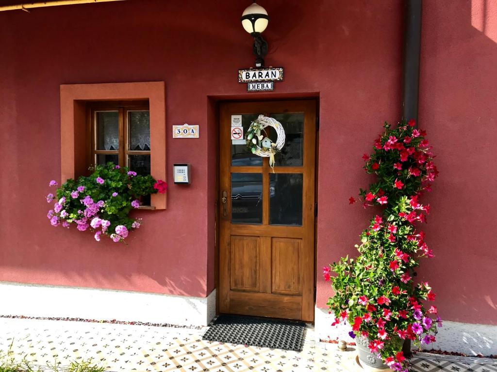 a red building with a wooden door and flowers at Ubytovanie Meba in Prešov