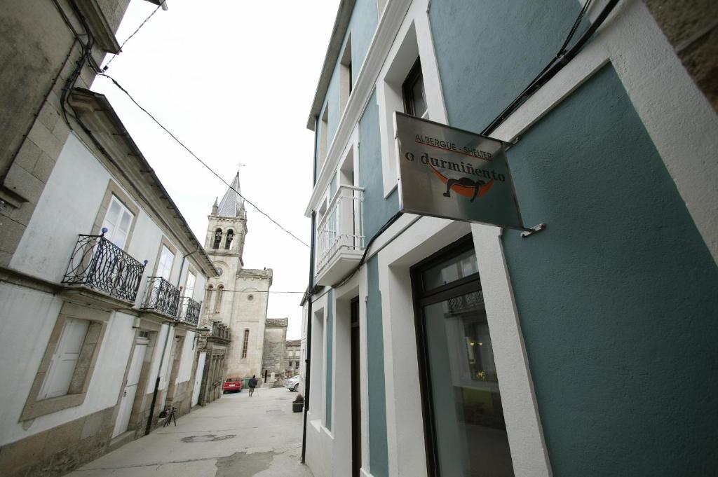 ein Schild für ein Restaurant an der Seite eines Gebäudes in der Unterkunft Albergue O Durmiñento in Sarria