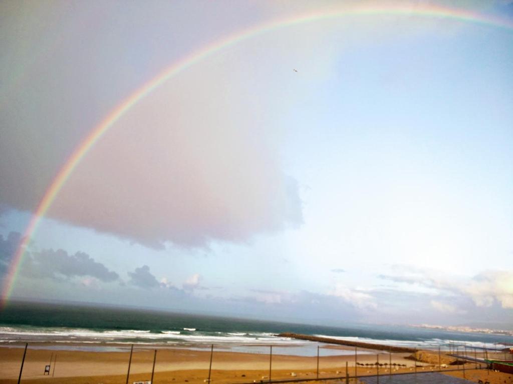 a rainbow in the sky over the beach at Amazing Apartment in Costa da Caparica in Costa da Caparica