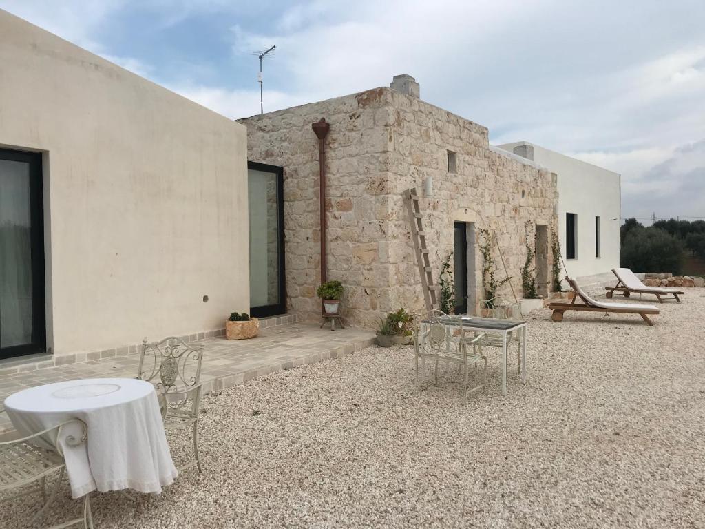 patio z krzesłami i stołem oraz budynek w obiekcie Relais Grottone w mieście Ostuni