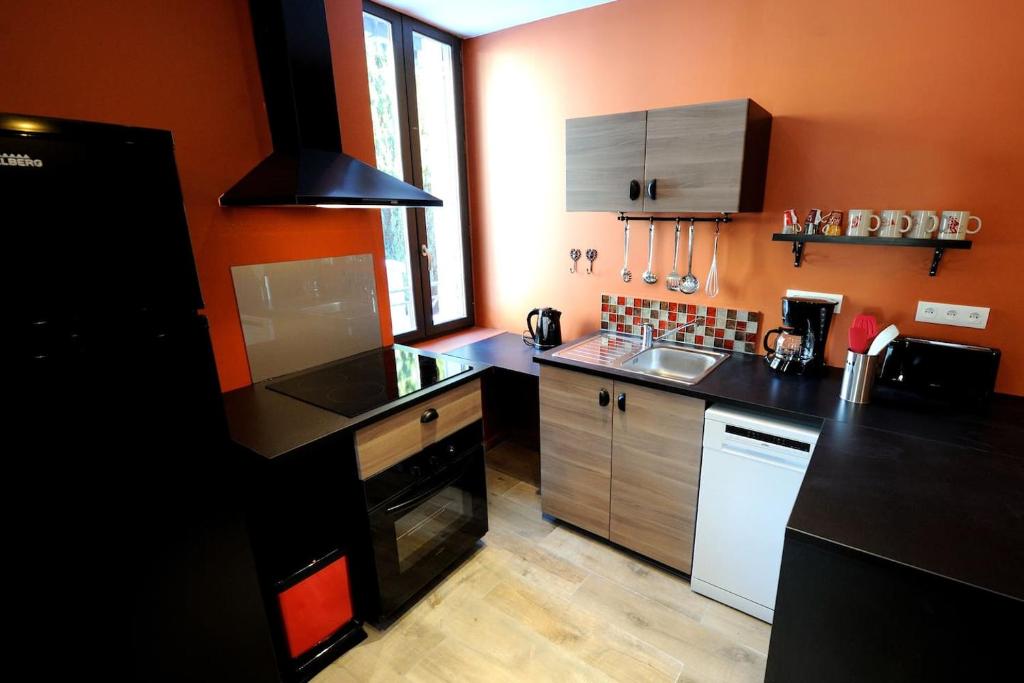 una cocina con encimeras negras y una pared naranja en Appartement Charlannes en La Bourboule