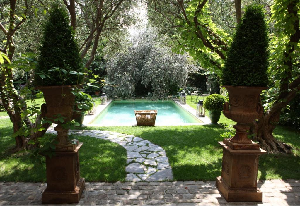 une piscine dans un jardin avec deux grandes plantes dans l'établissement Jardins Secrets, à Nîmes