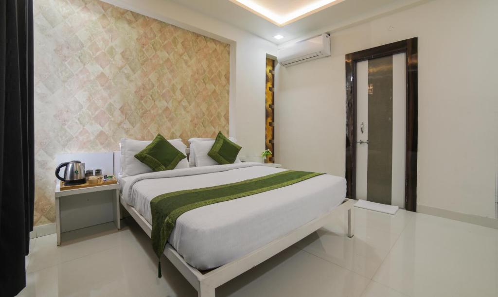 een slaapkamer met een groot wit bed met groene kussens bij Itsy By Treebo - Le Clover in Nagpur