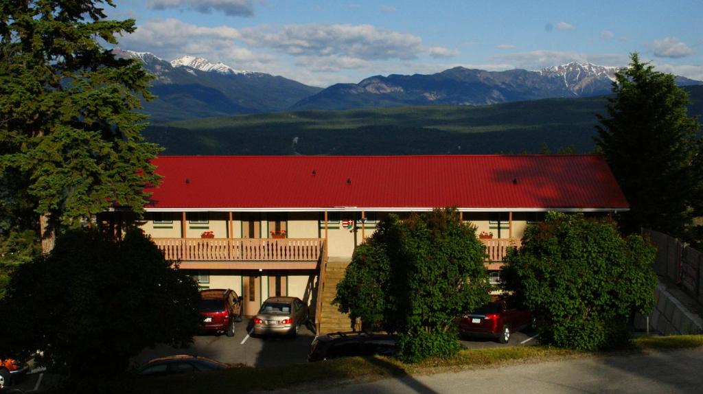 um edifício com carros estacionados num parque de estacionamento com montanhas em Rocky Mountain Springs Lodge em Radium Hot Springs