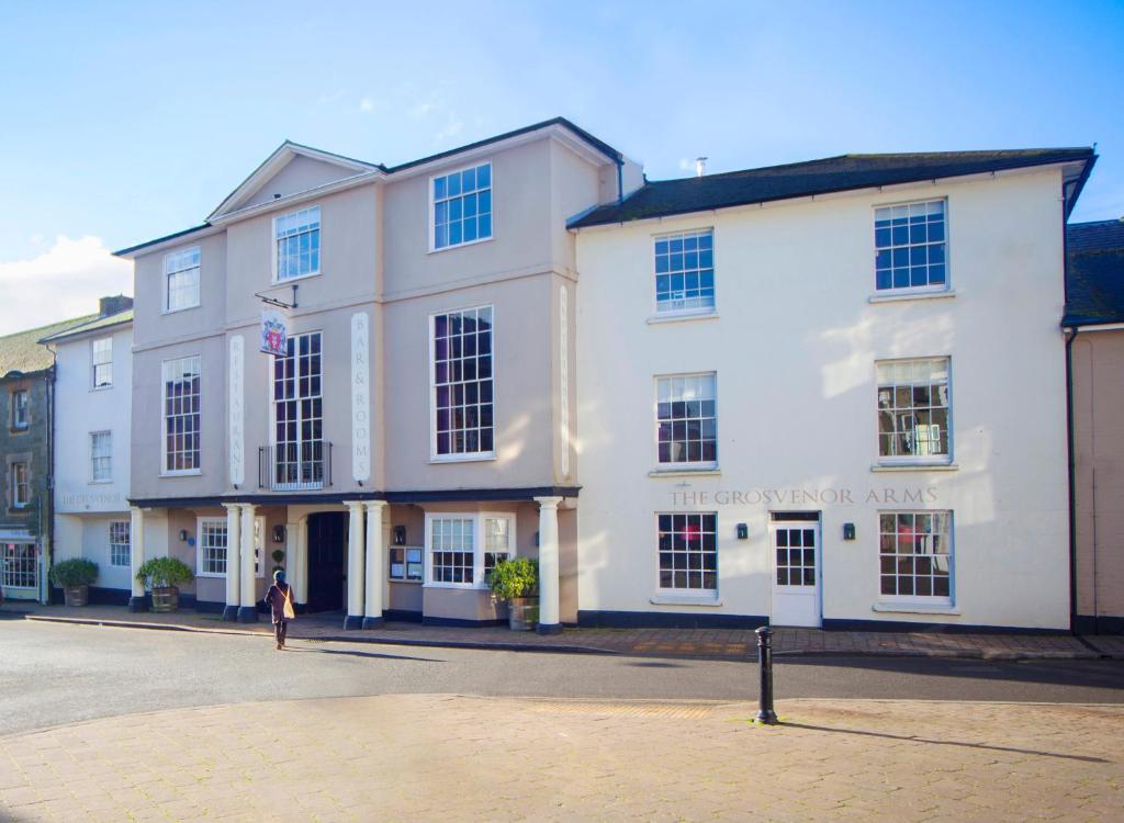 una mujer parada frente a un edificio blanco en The Grosvenor Arms en Shaftesbury