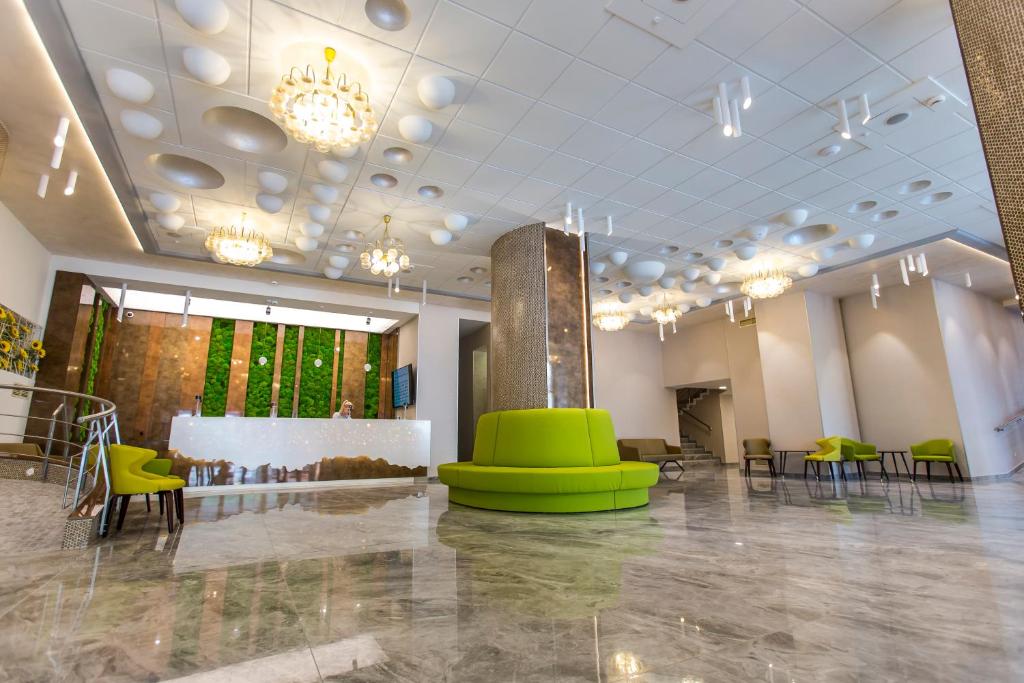 a large room with green chairs and tables and chandeliers at Hotel Olanesti & Spa Medical in Băile Olăneşti