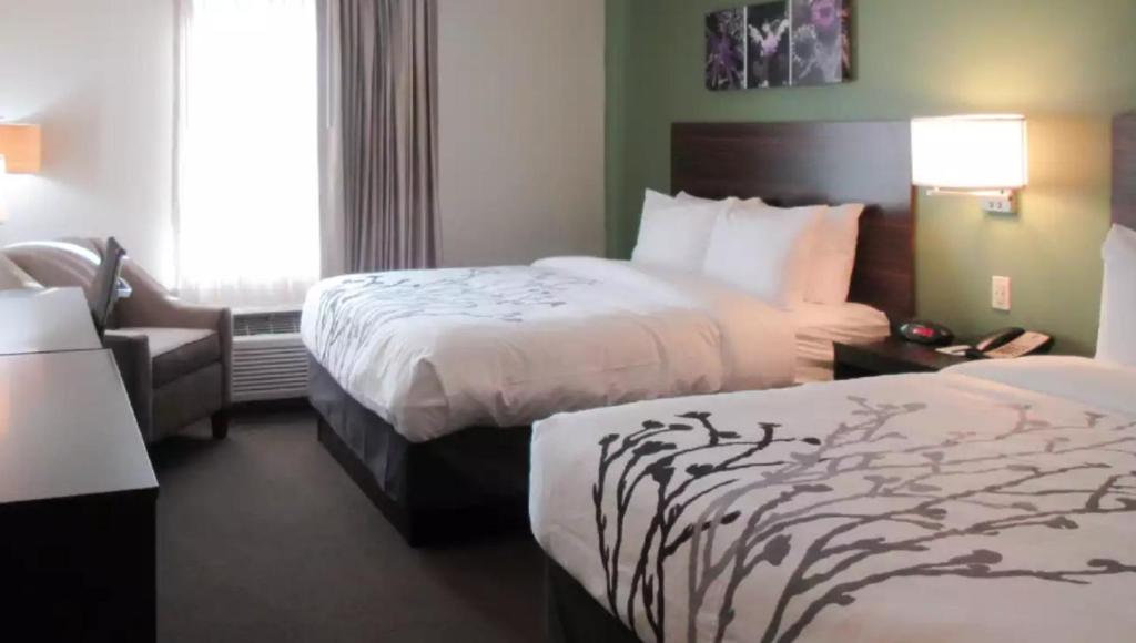una habitación de hotel con dos camas y una silla en Sleep Inn & Suites Chiloquin-Crater Lake Junction, en Chiloquin