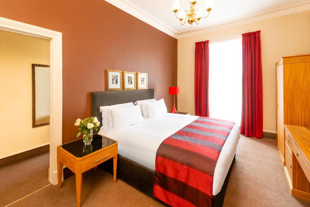 a hotel room with a large bed and a table with a vase at Millennium Hotel Glasgow in Glasgow