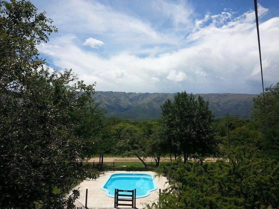 una piscina azul con árboles y montañas en el fondo en Cabañas Peñihue en Carpintería
