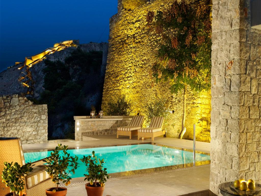 a swimming pool in front of a building with a wall at Nafplia Palace Hotel & Villas in Nafplio