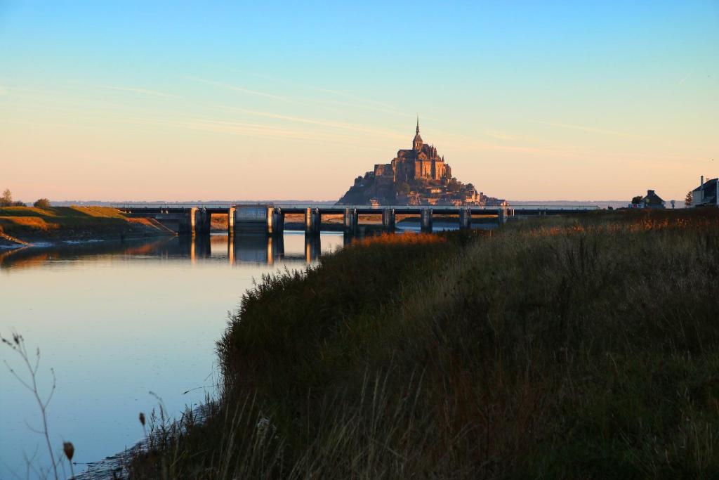 a castle on a bridge over a body of water at Le Mouton Blanc in Le Mont Saint Michel