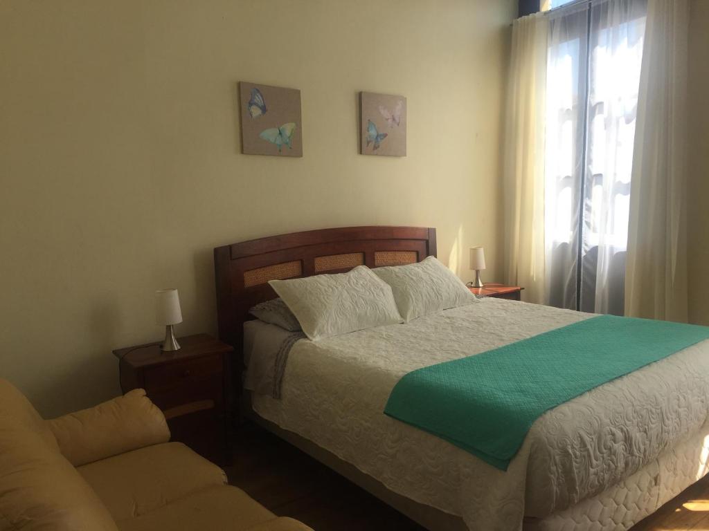 a bedroom with a bed and a couch and a window at Hostal Rama & CaStle in Valparaíso