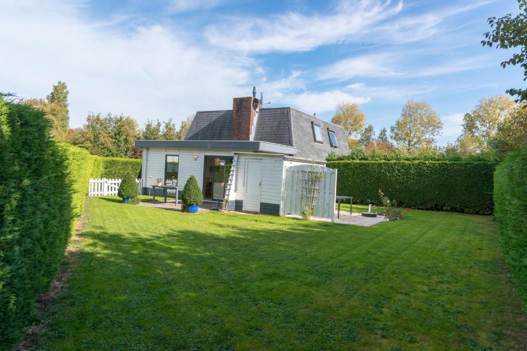una pequeña casa blanca con un patio de césped en Hello Zeeland - Vakantiehuis Zeester 66, en Breskens