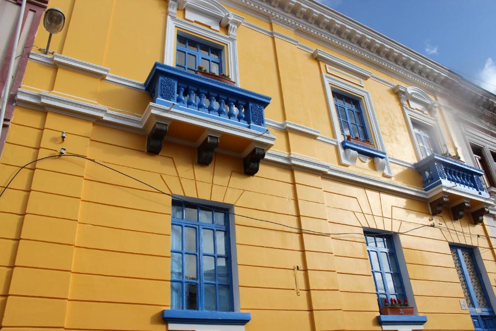 a yellow building with blue balconies and windows at Hostal Café Tiana in Latacunga