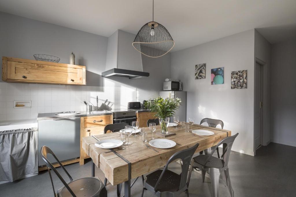 a dining room with a wooden table and chairs at L'ecume by Cocoonr in Saint-Coulomb