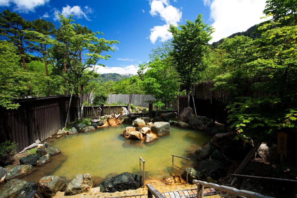 un bassin d'eau avec des rochers dans une rivière dans l'établissement Miyama Ouan Kyoritsu Resort, à Takayama