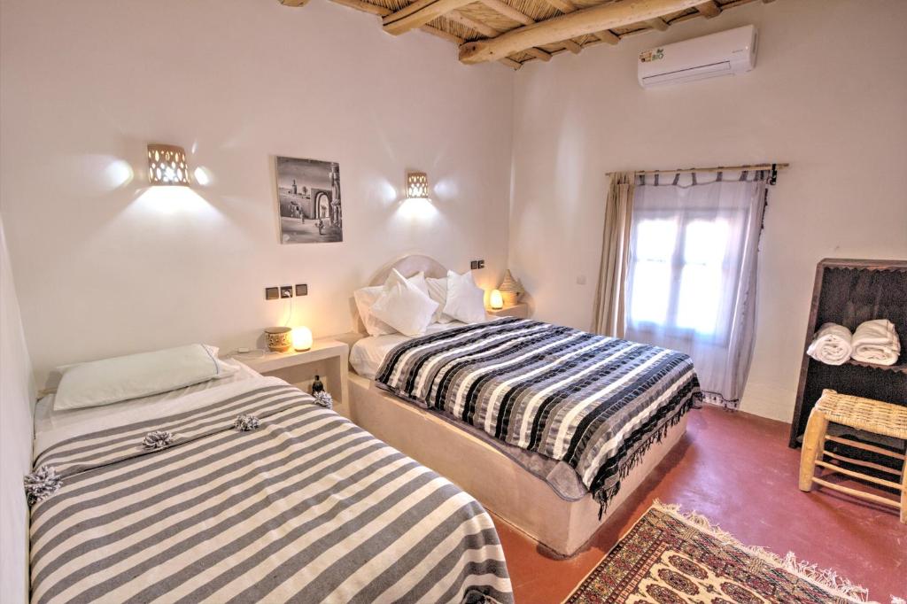 a bedroom with two beds and a window at MIGUIRNE Chez Ali in Tamellalt