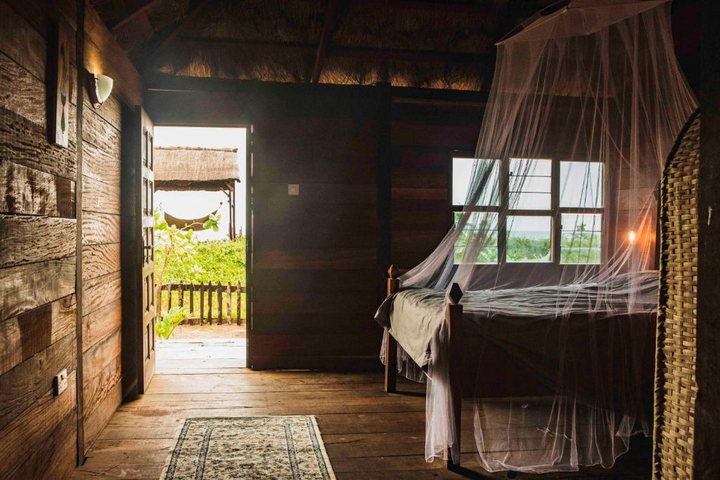 a bedroom with a bed with a mosquito net at Bees Mouth Gambia in Sanyang