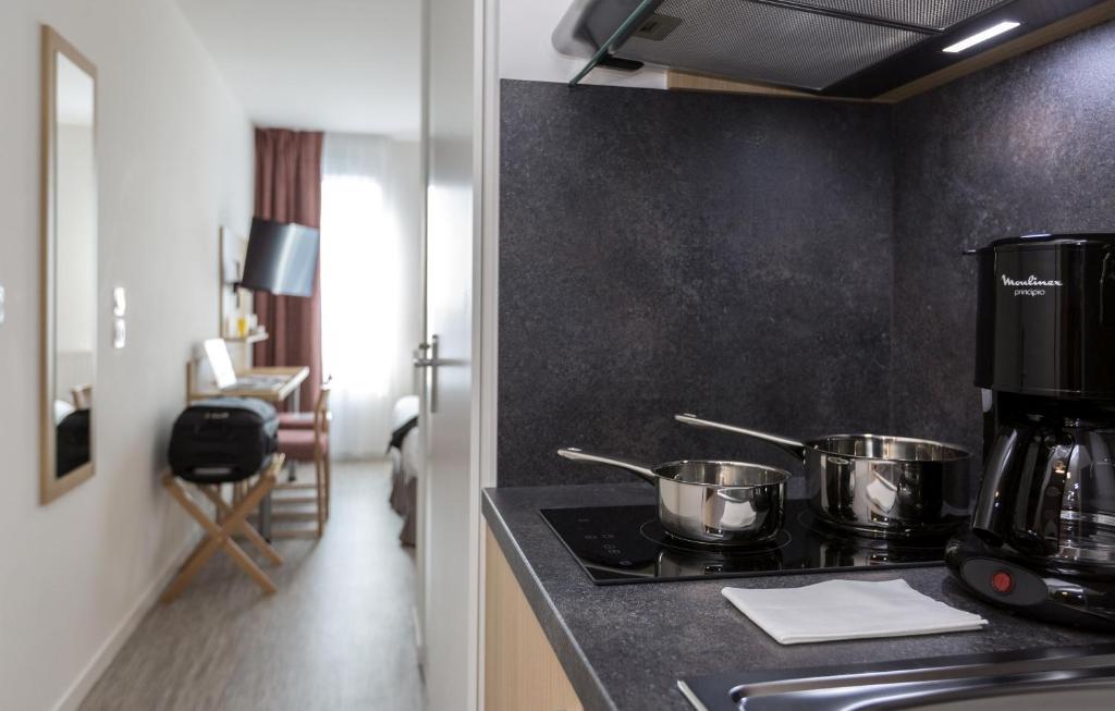 a kitchen with pots and pans on a stove at Résidence Odalys Nantes Cité des Congrès in Nantes