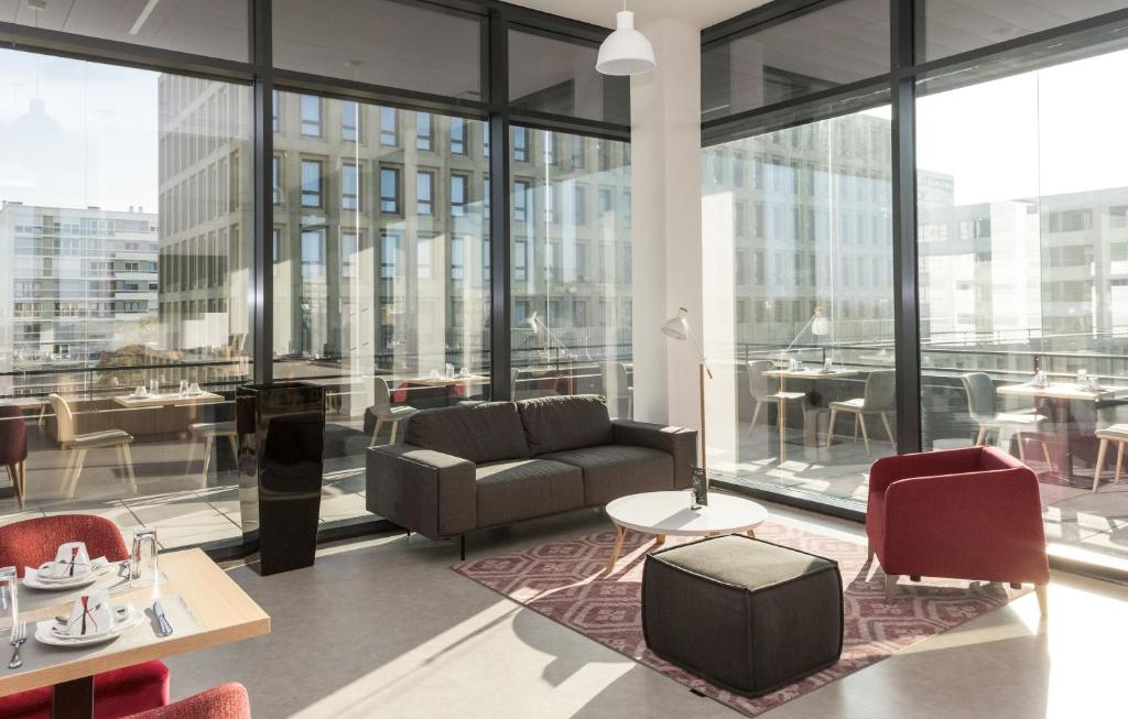 a living room with a couch and tables and windows at Résidence Odalys Nantes Cité des Congrès in Nantes