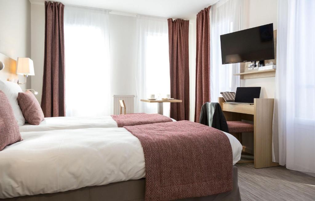 a hotel room with two beds and a television at Résidence Odalys Nantes Cité des Congrès in Nantes