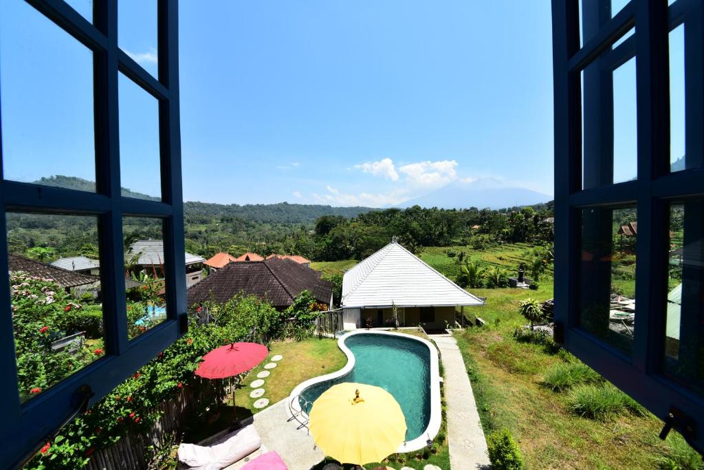 een raam met uitzicht op een zwembad met parasols bij Amrita Villa Sidemen in Sidemen