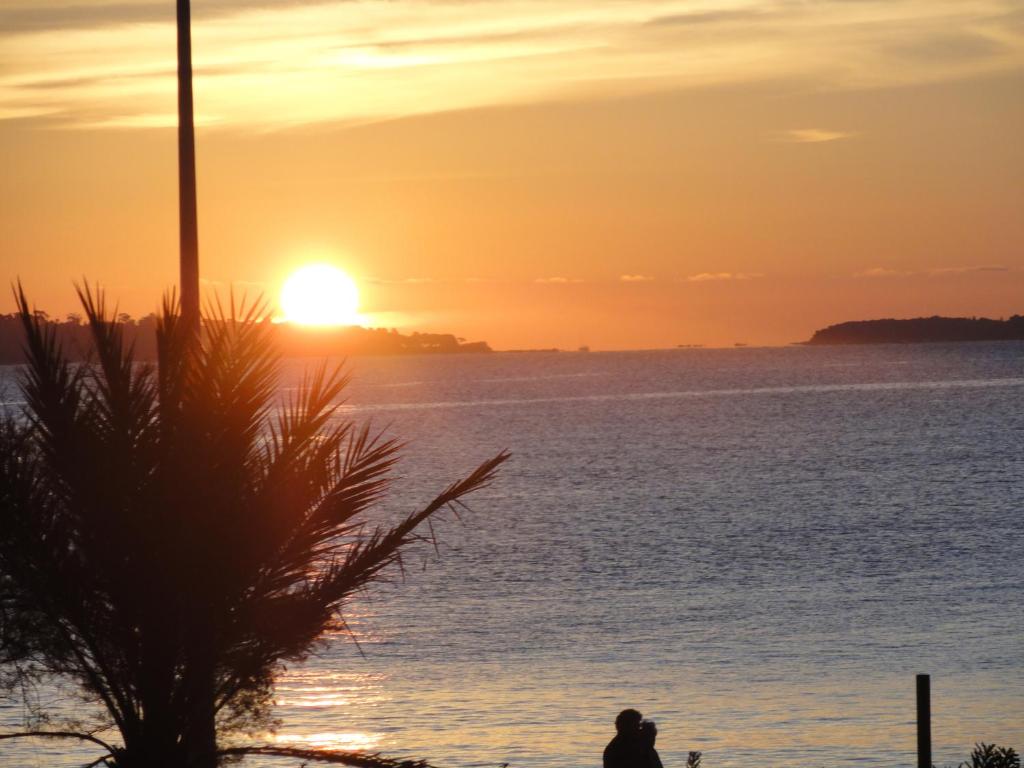 uma pessoa de pé em frente ao oceano ao pôr do sol em Cannes Terrace Beach Front & Sea view em Cannes