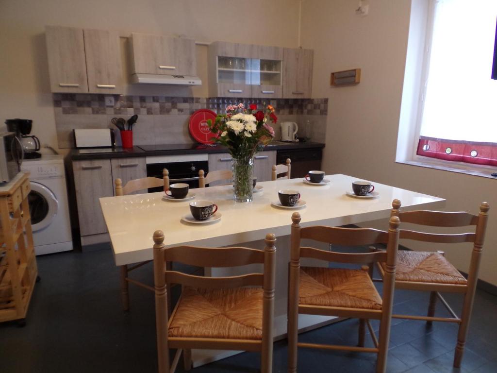 uma cozinha com uma mesa com cadeiras e um vaso de flores em L' éscale de la Besbre em Vaumas