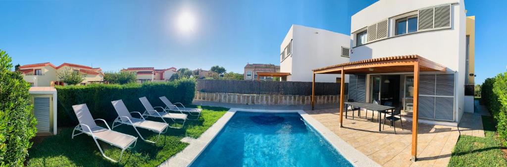 a backyard with a swimming pool and chairs and a house at Villa Lauvic in Cala en Bosc