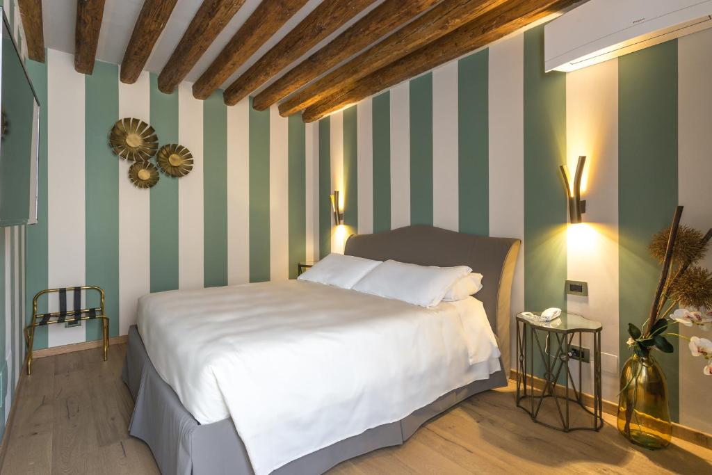 a bedroom with a white bed and striped walls at Hotel Tiziano in Venice