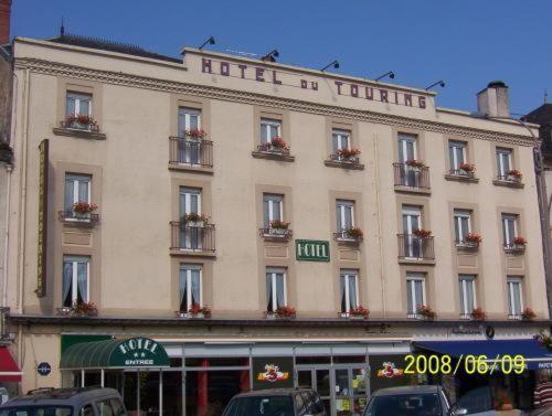 un grand bâtiment avec un hôtel en face dans l'établissement Hotel du Touring, à Saint-Céré